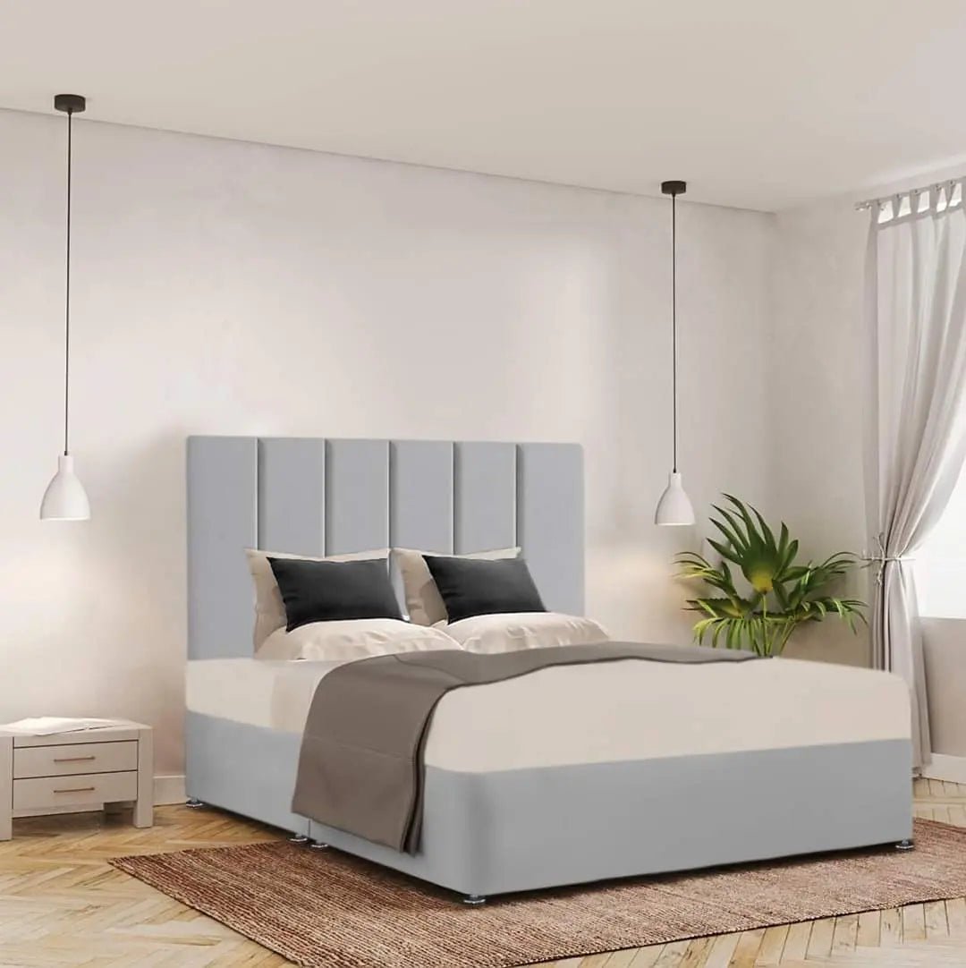 Pale grey upholstered bed with a vertical-panel headboard and low footboard in a bright bedroom