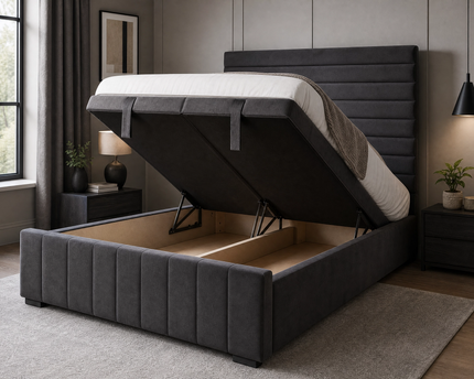 The Belmont Divan Ottoman Bed in charcoal grey velvet shown with end-lift storage mechanism open, revealing deep full-length storage cavity inside the upholstered divan base, featuring horizontal pleated headboard and vertical channel-stitched footboard